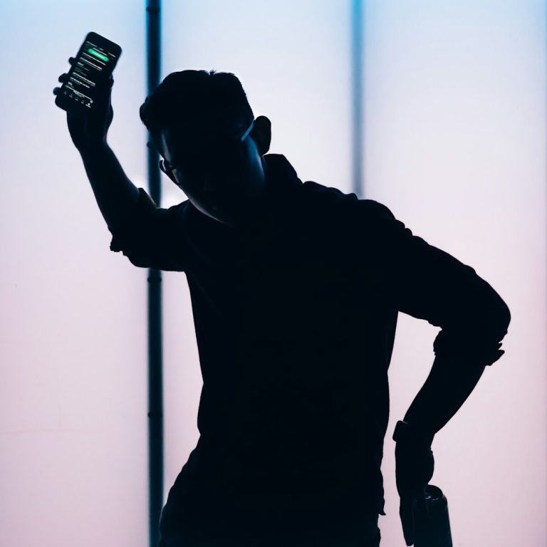 silhouette of man holding smartphone person receiving fraud alert on smartphone, security notification screen, worried expression