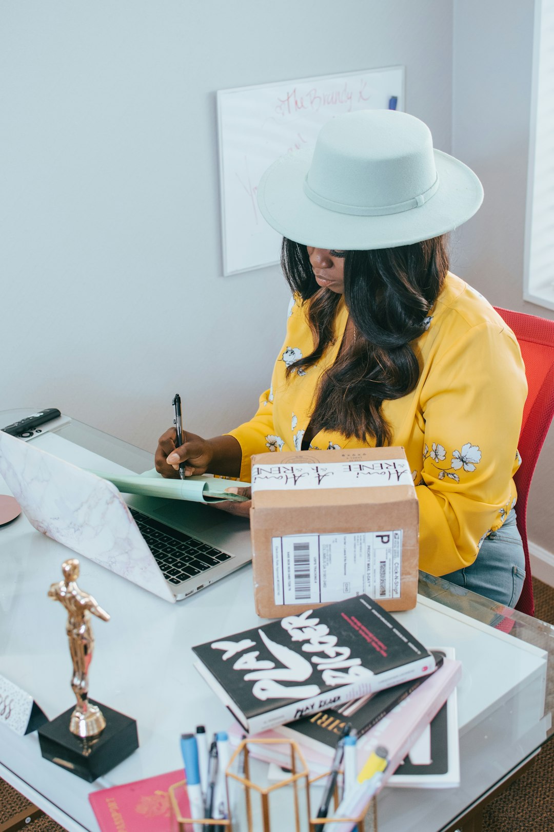 woman in yellow long sleeve shirt wearing white cowboy hat packing orders, small ecommerce, home workspace, products