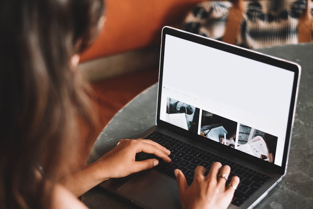 woman using macbook pro on table person editing article on laptop, review notes on screen, content optimization process