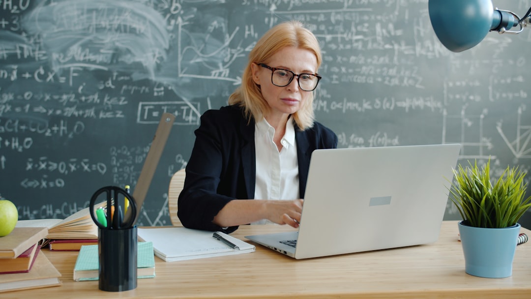 Woman working on a laptop in front of a chalkboard. student using laptop, plagiarism detection interface, academic writing desk