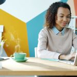 Young woman typing on laptop with coffee nearby freelancer laptop coffee home office
