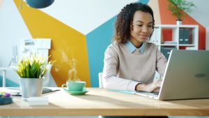 Young woman typing on laptop with coffee nearby freelancer laptop coffee home office