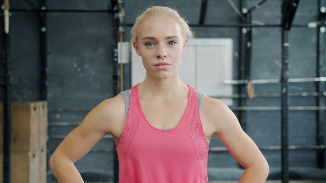 Young woman with blonde hair in gym breathing exercise, lip trill, warmup routine