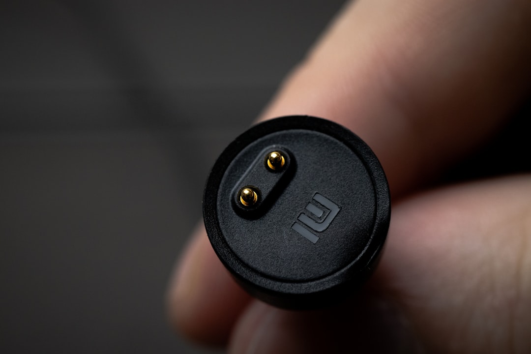 a close up of a person holding a black object surface charger, power adapter, magnetic connector
