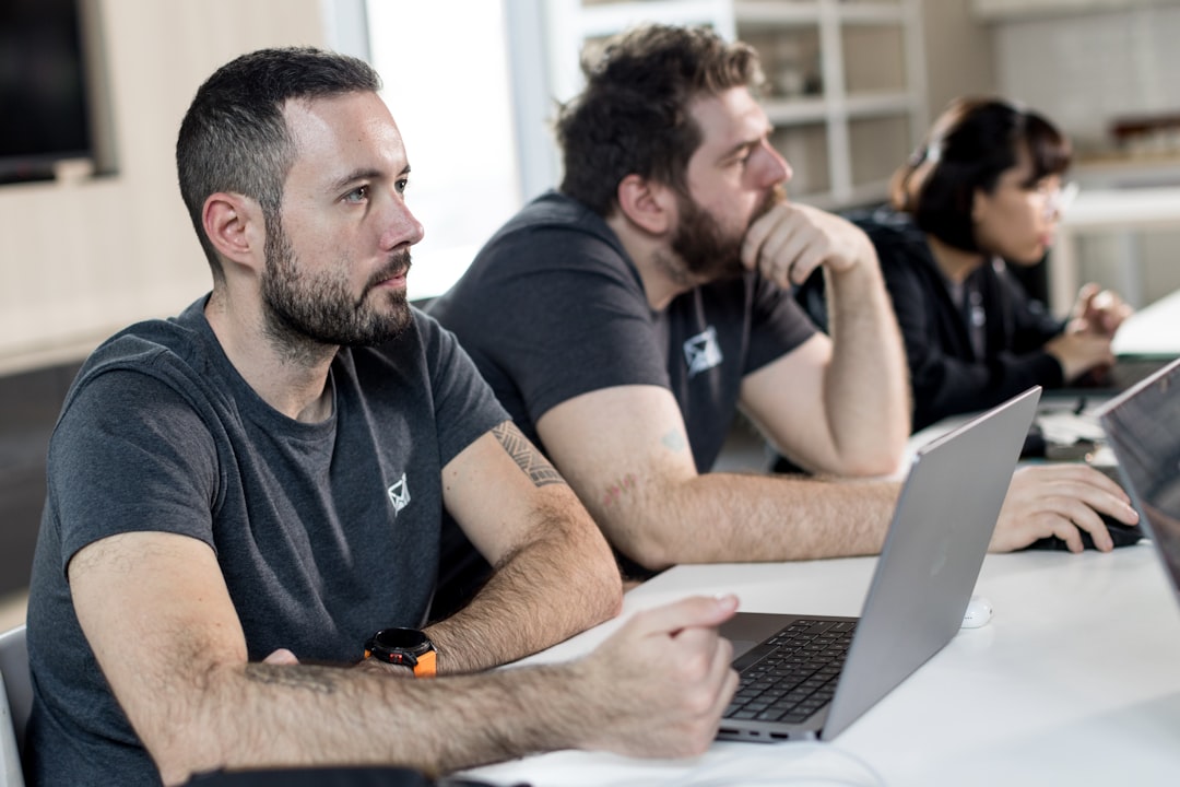 a group of men sitting at a table with laptops cybersecurity training, team meeting, data protection, secure habits
