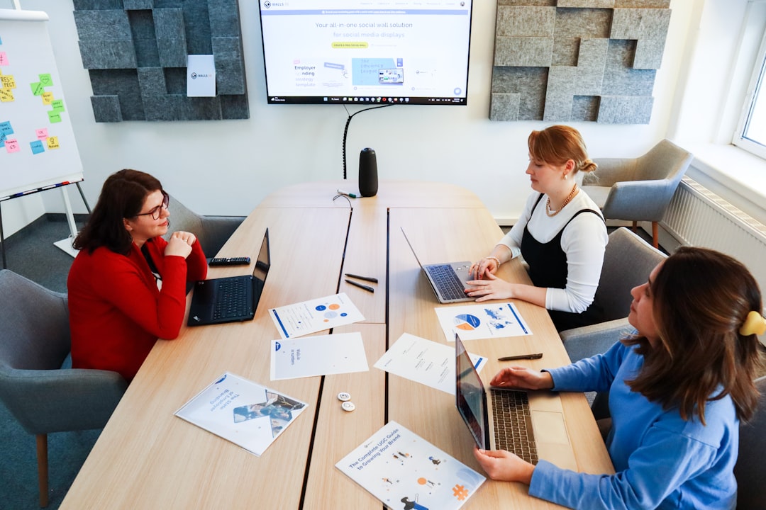 a group of women sitting around a table working on laptops software governance, risk management, team collaboration