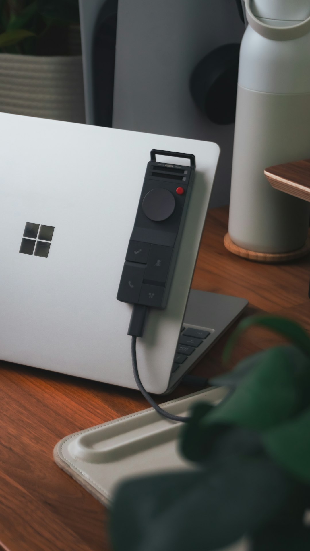 A laptop with a remote control attached. surface charger, power adapter, magnetic connector