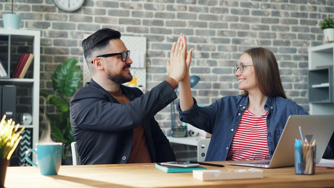 a man and a woman sitting at a table high fiving each other remote team, chat messages, collaboration workspace
