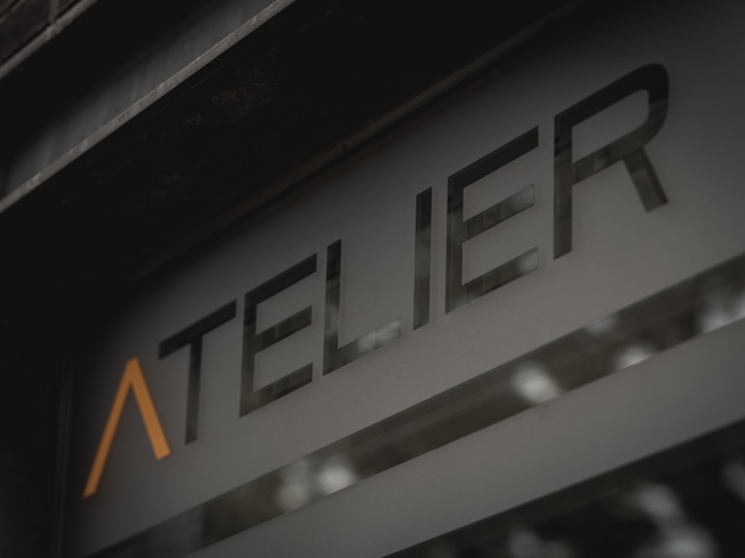 Atelier sign with stylized orange 'a' on a dark surface. minimal store sign, quiet luxury, modern branding, simple facade