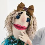 closeup photo of person holding peppet colorful puppets, puppet theater, character names