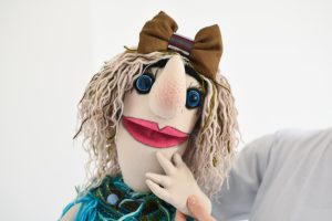 closeup photo of person holding peppet colorful puppets, puppet theater, character names