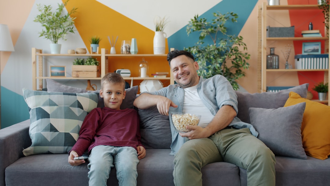 Father and son watching TV with popcorn. family movie night, popcorn, streaming service, sofa