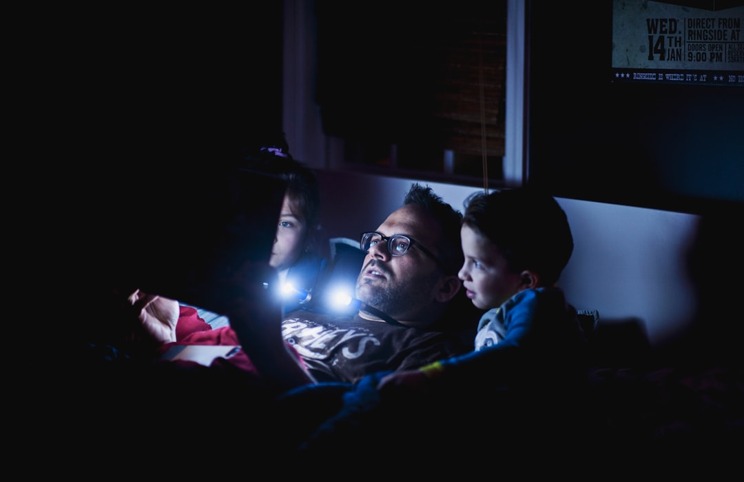 man in blue shirt lying on bed family movie night, popcorn, streaming service, sofa