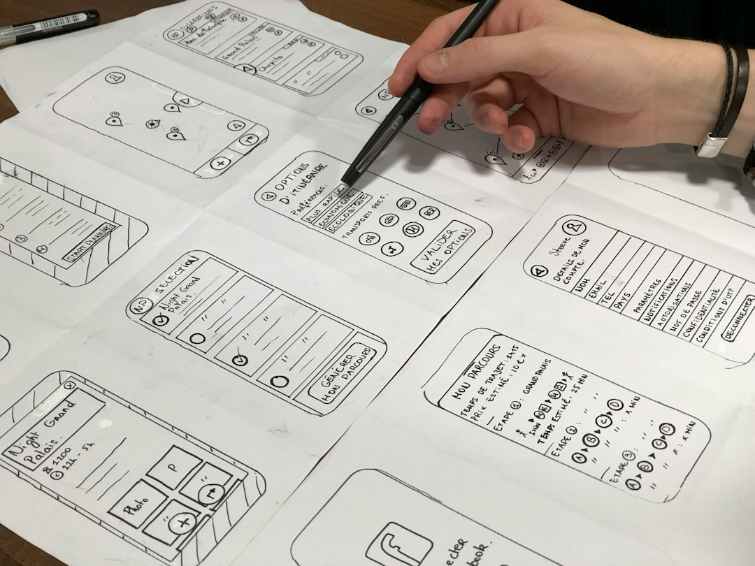 person holding pen near paper design team collaboration, wireframes, browser interface