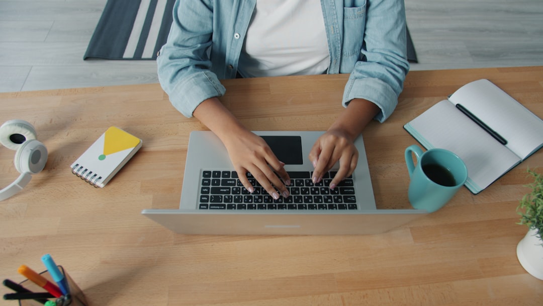Person typing on a laptop at a wooden desk. cloud security, remote workers, identity protection
