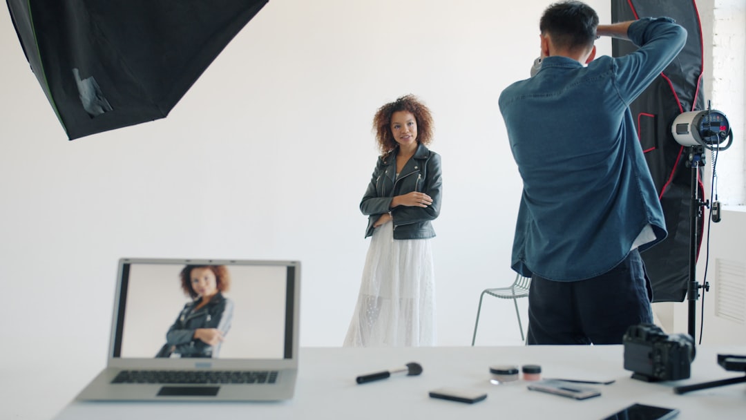 Photographer taking picture of model in studio green screen studio, fabric backdrop, video production