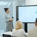 Woman presenting a graph to an audience conference stage, keynote speaker, business analytics