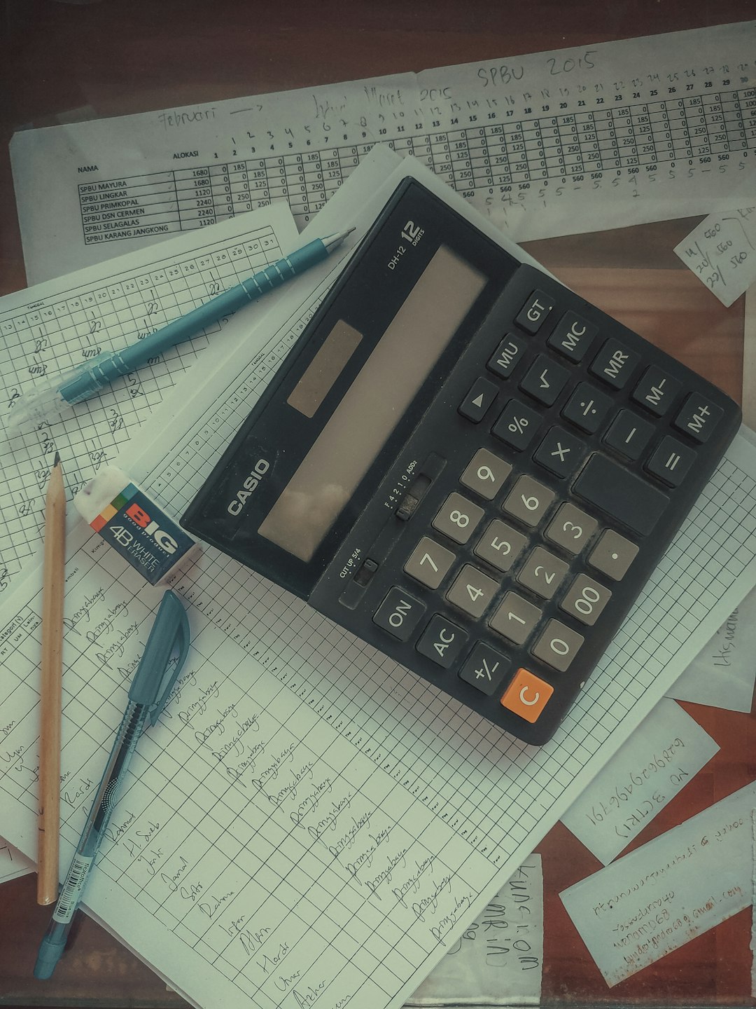 a calculator sitting on top of a pile of papers calculator, invoice, revenue numbers