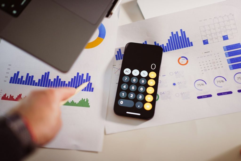 a calculator sitting on top of a table next to a laptop pricing chart, resource planning, cloud costs, calculator