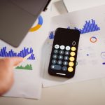 a calculator sitting on top of a table next to a laptop pricing chart, resource planning, cloud costs, calculator
