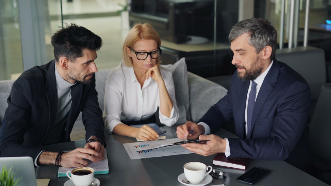 a group of people sitting around a table audit meeting, compliance documents, office discussion