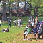 a group of people sitting on top of a park bench team picnic, summer park, coworkers, outdoor lunch