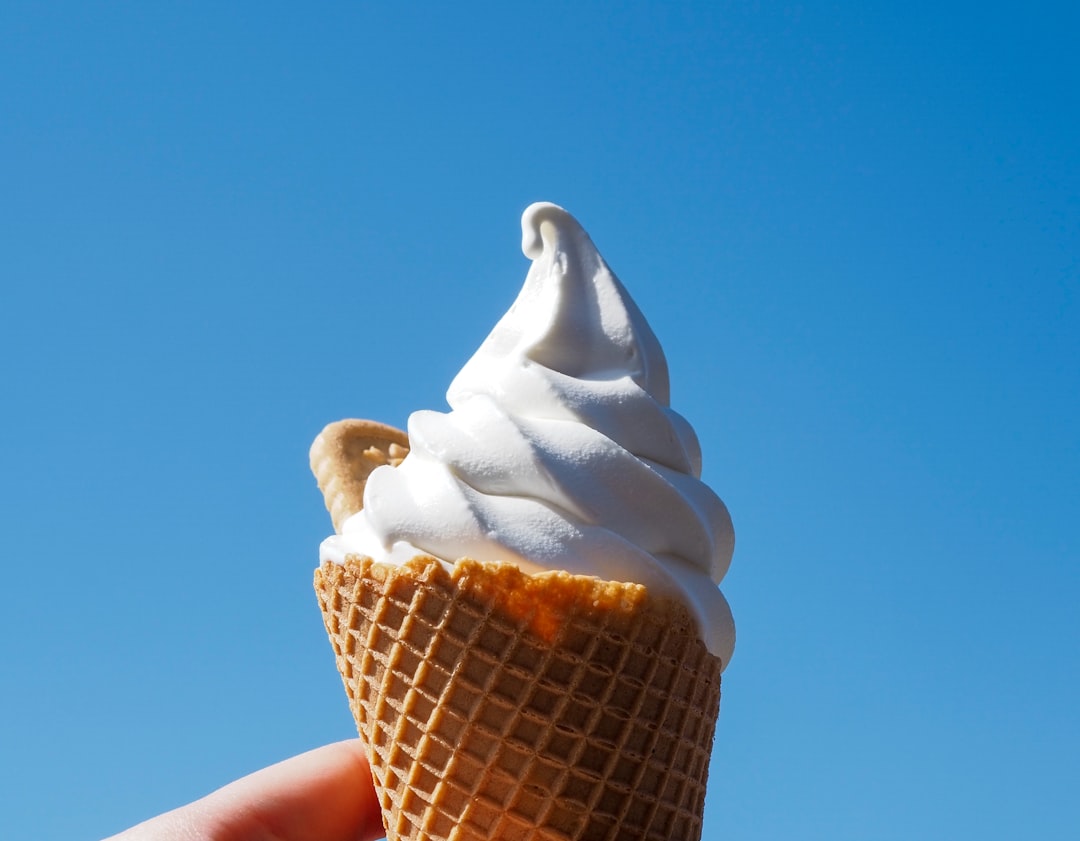 a hand holding an ice cream cone in front of a blue sky ice cream, sunburn, sunny day, correlation example