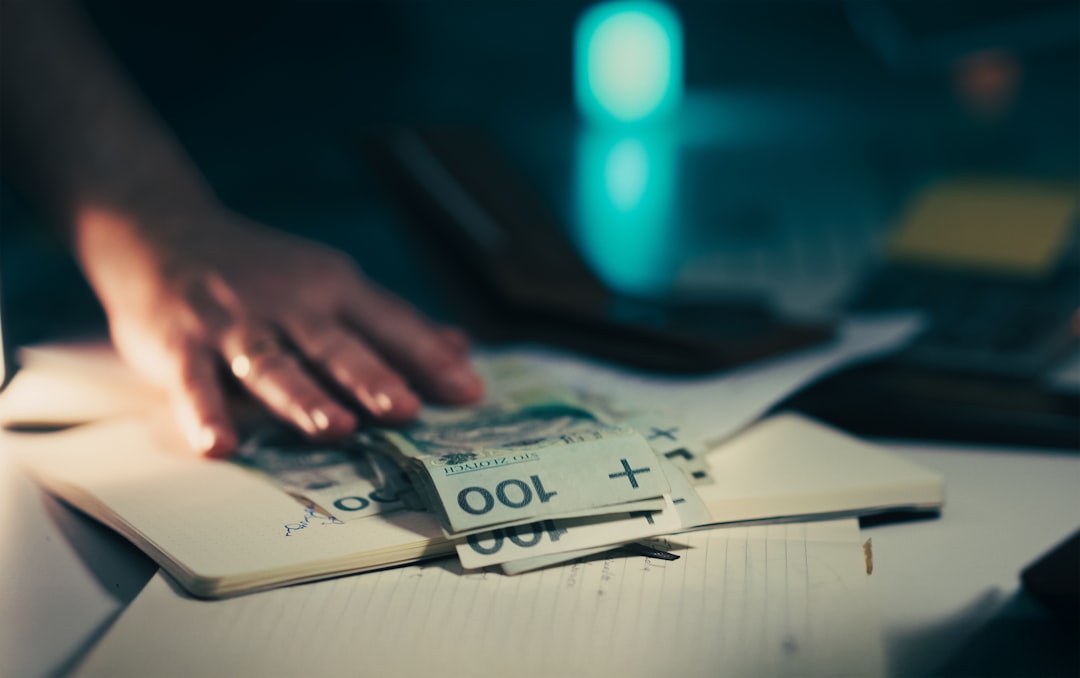 A hand reaching for money on a notebook. business risk, money papers, worried owner