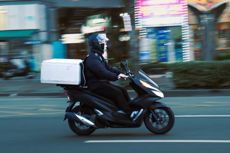 a man riding a scooter with a box on the back of it order tracking, delivery scooter, mobile notification