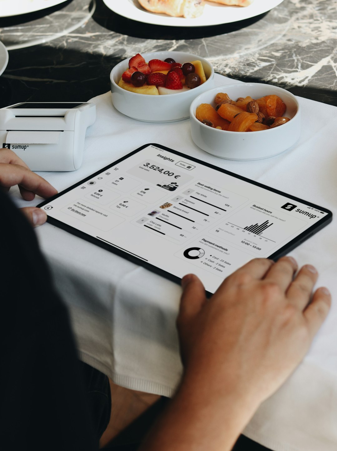 A person sitting at a table with a tablet restaurant software, sales analytics, tablet pos, menu reports