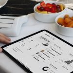 A person sitting at a table with a tablet restaurant software, sales analytics, tablet pos, menu reports