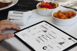 A person sitting at a table with a tablet restaurant software, sales analytics, tablet pos, menu reports