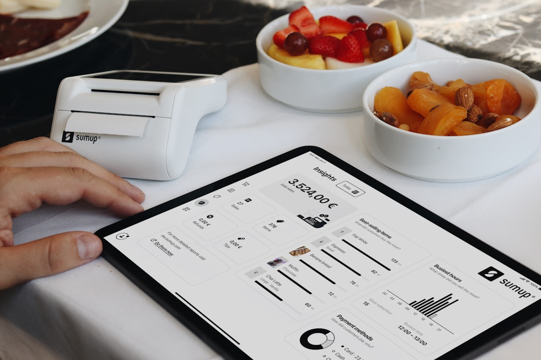 A person sitting at a table with a tablet restaurant software, sales analytics, tablet pos, menu reports