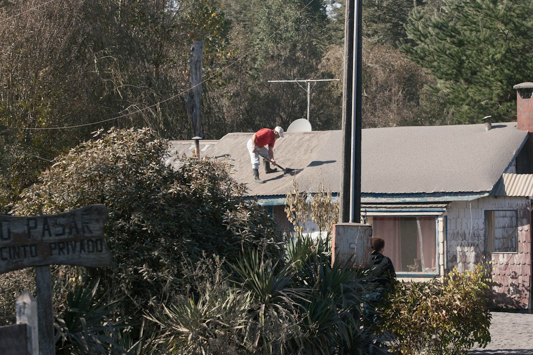 A person works on a roof in a rural setting local neighborhood, home repair, service van, happy customer