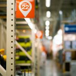 a sign that is on a shelf in a store warehouse shelves, packing boxes, shipping labels