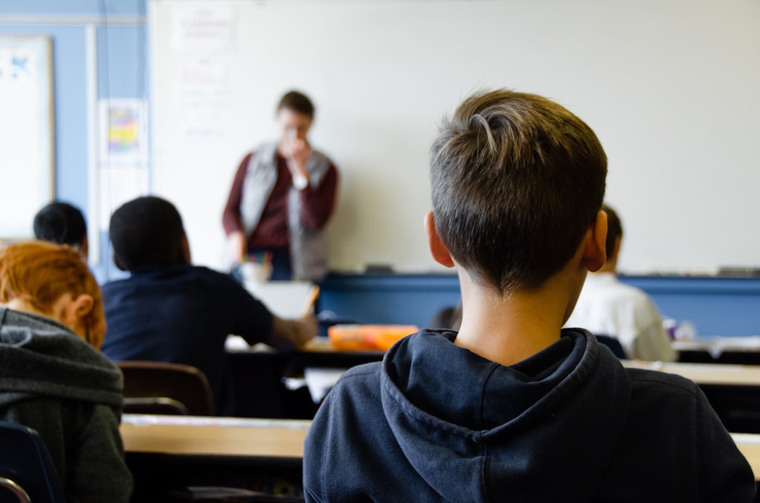 boy in black hoodie sitting on chair students classroom teacher books
