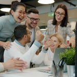 Diverse team celebrating success at office desk. happy team, delivery train, software launch, success