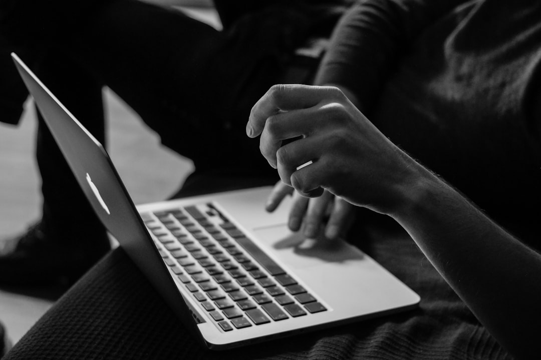 grayscale photo of person using MacBook online course laptop learning