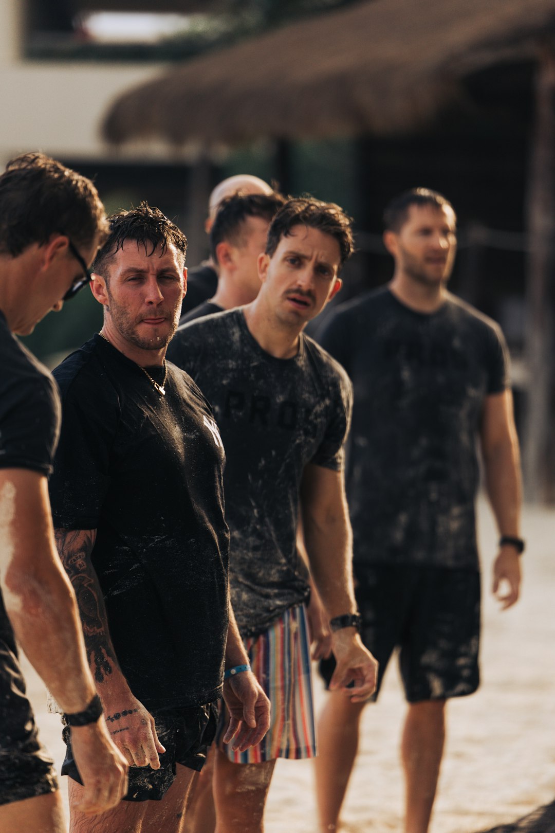 Group of men standing together outdoors, wet and looking forward. team challenge, outdoor activity, coworkers solving clues, summer event
