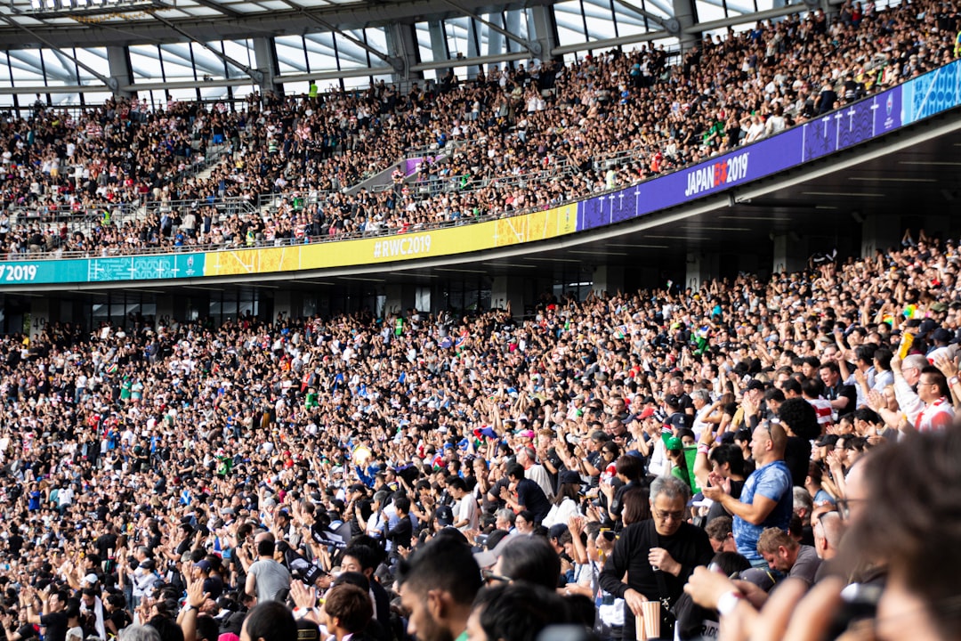 people at the bleachers of the stadium sports fans, mobile streaming, scoreboard, arena