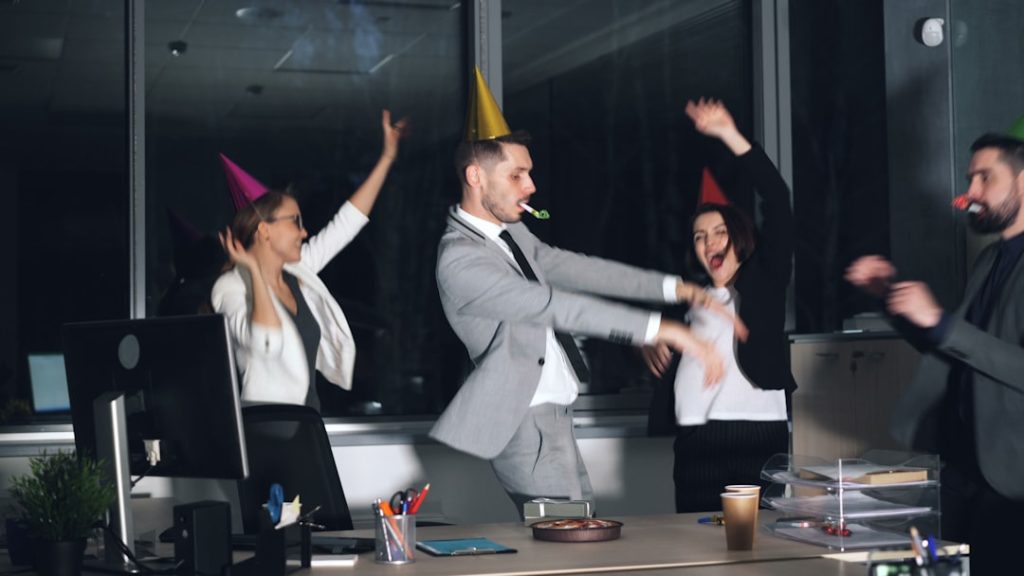 People in party hats dancing in an office at-work celebration. employee recognition, virtual meeting, team appreciation, workplace celebration