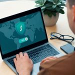 person using macbook pro on white table cybersecurity dashboard, laptop protection, safe software