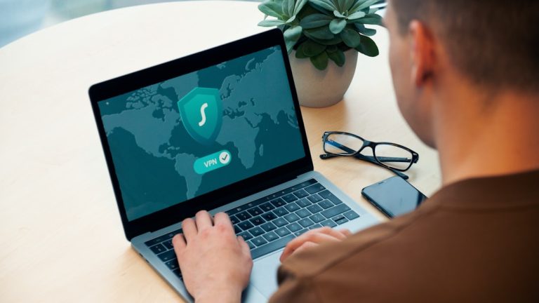 person using macbook pro on white table cybersecurity dashboard, laptop protection, safe software