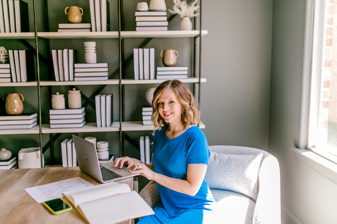 Smiling woman working on laptop at a desk small business owner, email comparison, office desk