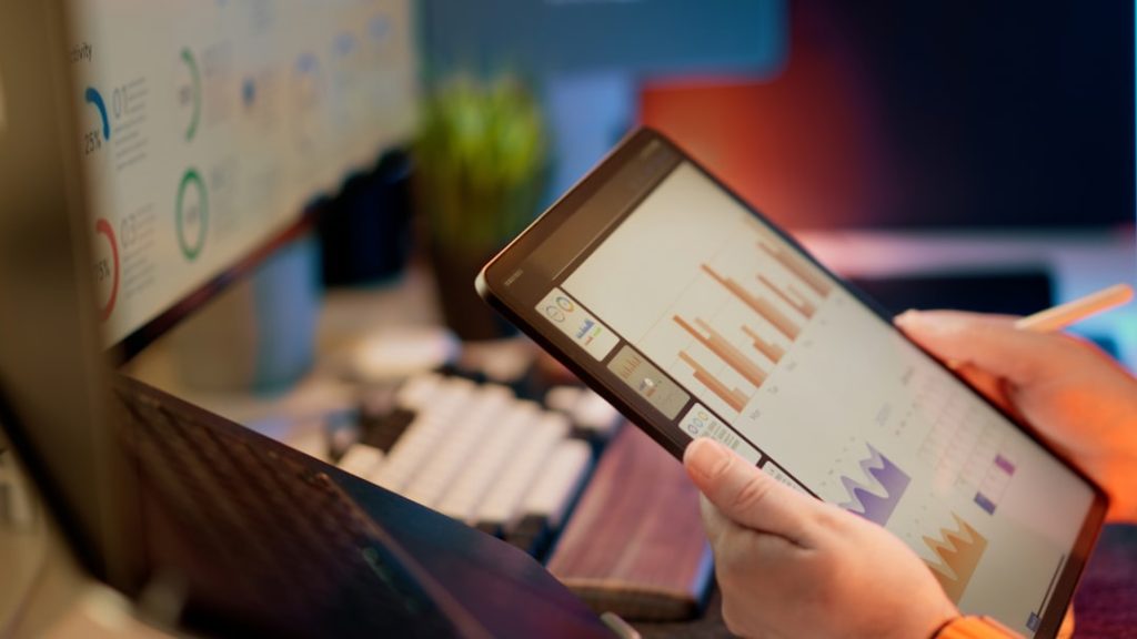 Someone analyzes financial data on a tablet. mobile advertising, user engagement, app analytics