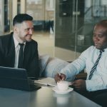 Two businessmen discussing documents over coffee legal team reviewing contract office