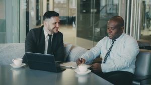 Two businessmen discussing documents over coffee legal team reviewing contract office