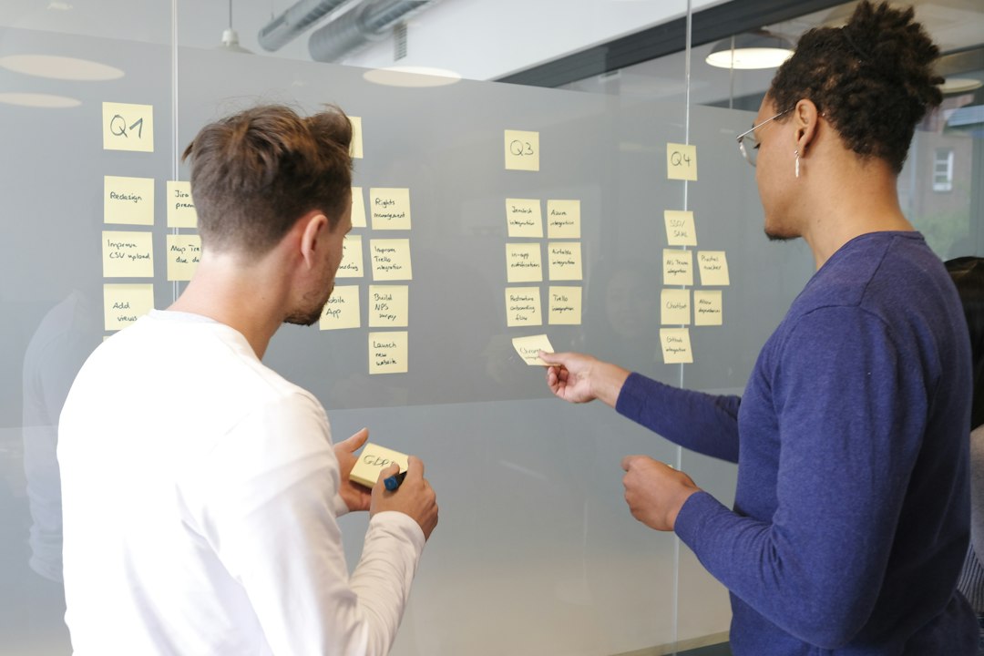 Two people collaborating on a project plan using yellow sticky notes on a glass wall mvp planning, feature list, startup team