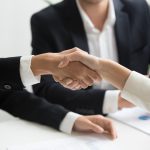 two people shaking hands in front of a laptop business meeting, professional services, client trust