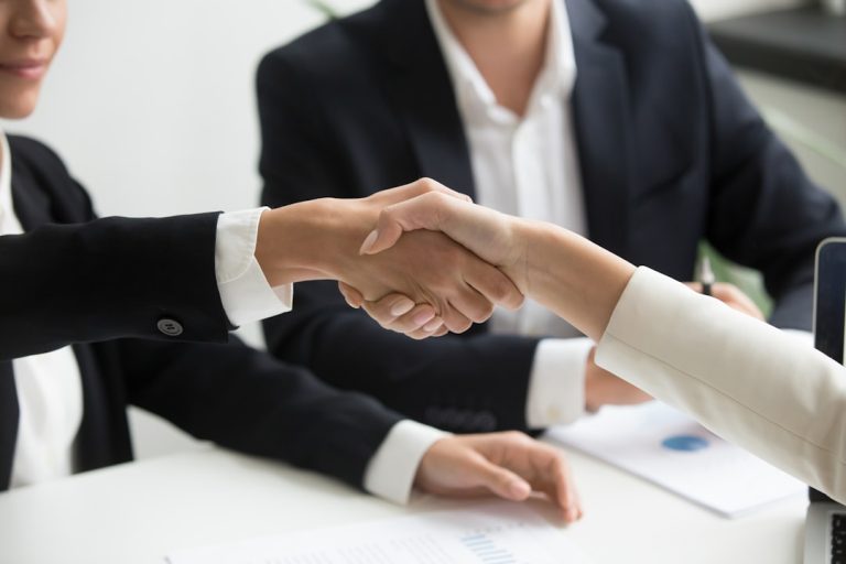 two people shaking hands in front of a laptop business meeting, professional services, client trust